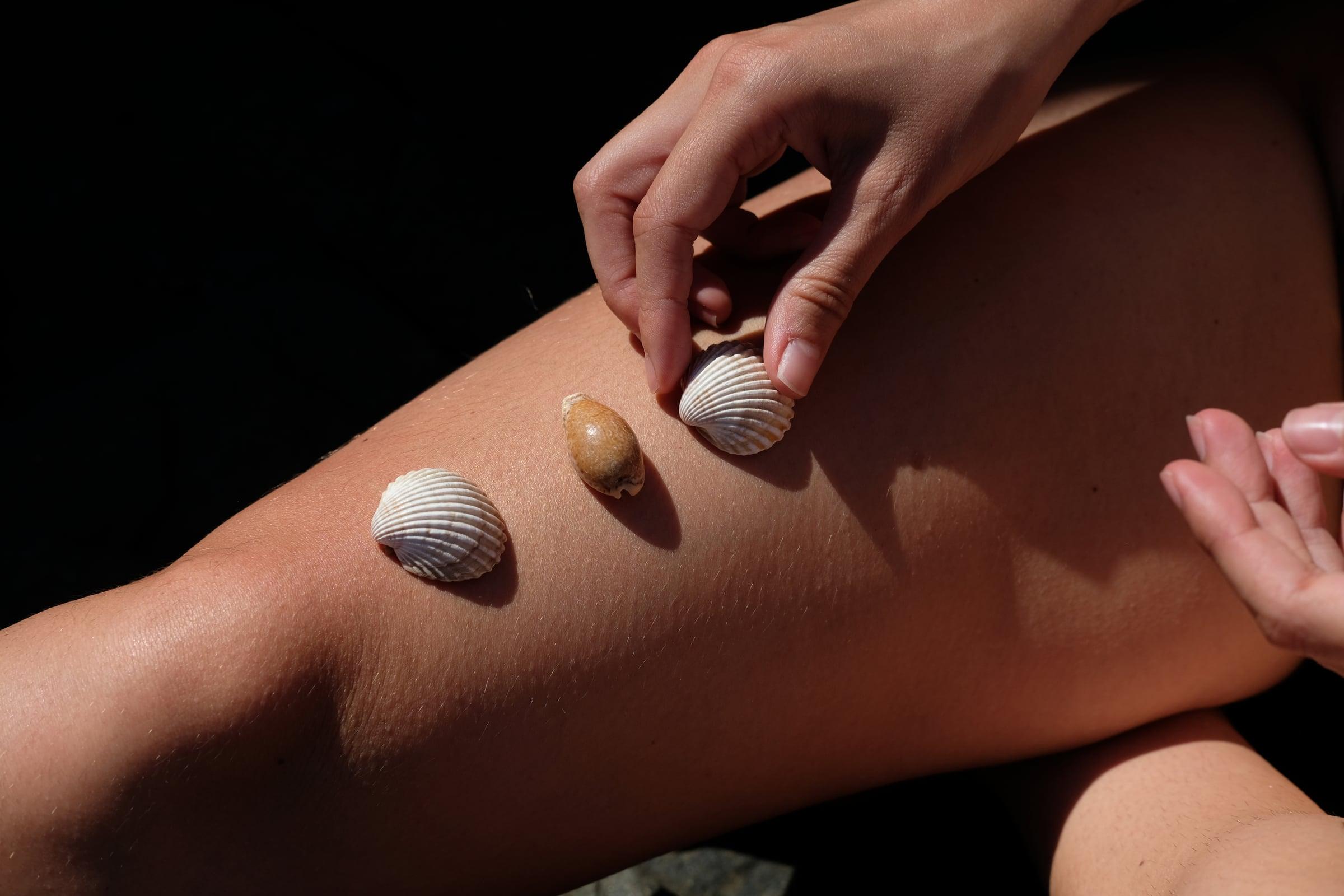 Tres conchas de mar sobre una pierna de mujer
